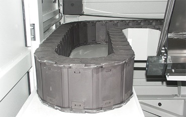 Niente più segni di bruciatura: la catena portacavi chiusa in polimero realizzata con il materiale speciale "igumid HT". L'alimentazione di energia resiste a trucioli fino a 850°C.